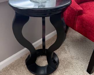 black accent table featuring a distinctive curved base and a round top. 