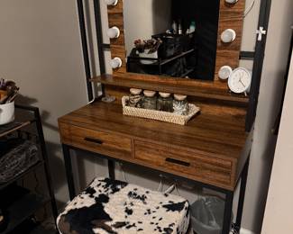 rustic brown industrial-style makeup vanity set with a lighted mirror and cow print stool