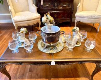($300- French coffee table- 40x20.5x16), ($200- footed silver-plate champagne bucket), ($100- Italian mid-century etched glass serving tray), ($1200- set of 3- Capodimonte Guiseppe Cappe figurines "Putti with Wine"- average height 12-6.5"), ($80- set of 8- etched brandy glasses)