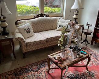 Carved wood upholstered camelback sofa, glass top coffee table