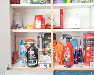 a variety of automotive cleaning and maintenance products stored on shelves, including bottles of Rain-X glass treatment, Turtle Wax rubbing compound