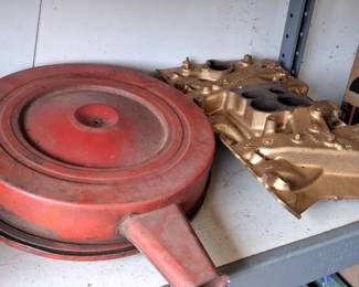vintage air cleaner assembly, likely for a 1960s Mopar or Chevrolet vehicle.The gold-colored part is a cast iron intake manifold, consistent with those used on Chevrolet small-block or big-block engines