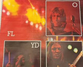 This photograph shows a vintage Pink Floyd album poster featuring images of the band members and a live concert scene. The poster is associated with the release of their 1973 album "The Wall"