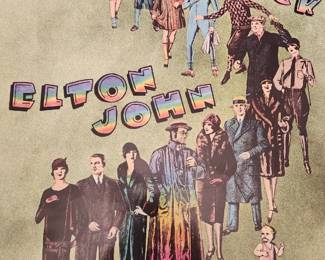 This vintage promotional poster features Elton John and his band members walking in a colorful, retro fashion, with the title "Crocodile Rock" written in bold, rainbow-colored letters. The image was used for the 1973 MCA Records release of the hit single, which became one of his first U.S. number-one singles