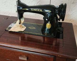 Singer sewing machine mounted on a wooden cabinet - Singer brand founded in 1850.
