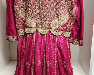 Pakistani bridal dress in a vibrant pink hue, featuring intricate gold embroidery, sequins, and a flowing skirt