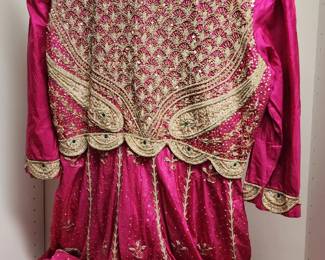 Pakistani bridal dress in a vibrant pink hue, featuring intricate gold embroidery, sequins, and a flowing skirt