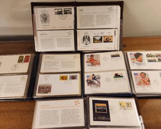 First Day Covers and commemorative stamps arranged in protective sleeves. The covers feature various international themes, including sports, cultural events, and historical milestones, each marked with a unique postmark.