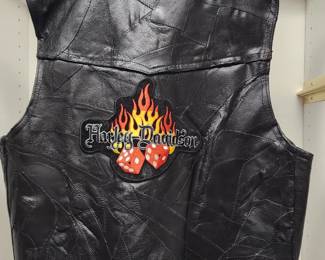 Black leather motorcycle vest featuring a bold flame graphic with the Harley-Davidson logo and two red dice