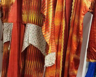 Vibrant Uzbek ikat chapan robes in rich orange and yellow tones