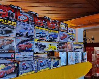 AMT and other diecast model car kits arranged on a table, featuring a variety of classic and modern vehicles. The collection includes models such as the 1961 Impala SS 409, 1972 Pontiac Firebird, and 1961 Corvette