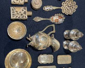 A premier assortment of sterling silver smalls, including silver-clad glass scent bottles, ornate heraldic spoons with enamel crests, and vintage match safes