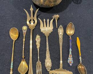 An exceptional collection of antique specialty silver featuring a large embossed presentation bowl, ornate cold meat forks, and exquisite enamel-handled demitasse spoons