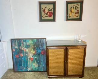 Retro wood cabinet with wicker-panel doors shown next to vibrant abstract floral art.