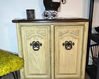 Elegant cream-colored French Country cabinet with ornate dark hardware