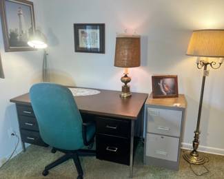 Steel-frame desk, teal rolling chair, and multi-functional lamps