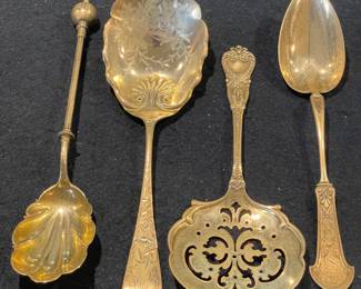 A stunning set of four gold-washed (vermeil) sterling silver serving spoons featuring intricate floral engravings and a shell-motif bowl