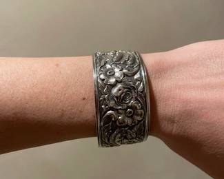 A stunning vintage sterling silver wide-band cuff bracelet featuring a deeply embossed, high-relief rose and floral pattern
