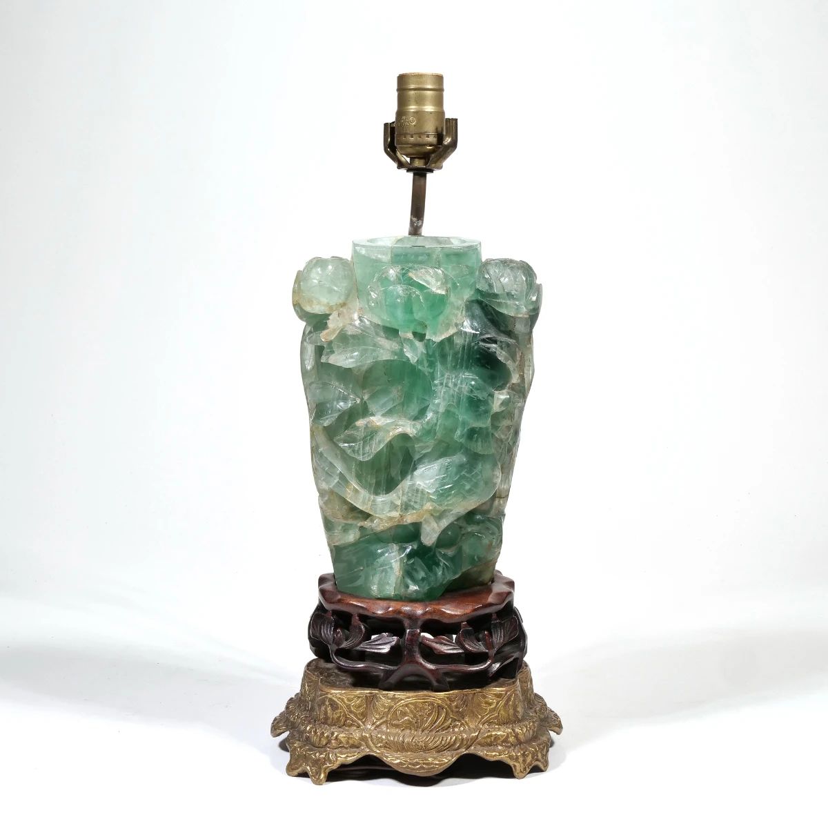 CHINESE CARVED GREEN QUARTZ VASE / LAMP | A carved green quartz vase or jar on a carved wood stand, mounted and electrified on decorative brass footing, the carving depicting a bird amongst flowering branches