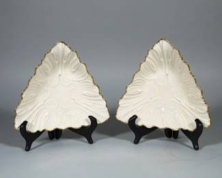 (2pc) LENOX PORCELAIN TRIANGULAR LEAF-FORM DISHES WITH GILT RIM | Pair of cream-colored triangular leaf-form porcelain dishes by Lenox, each molded with stylized leaf/petal relief and a scalloped gilt rim. Underside bears a printed Lenox wreath-and "L" backstamp with "MADE IN USA." Each measures 7.25 in. (dish edges). Glazed finish and sold as a pair.