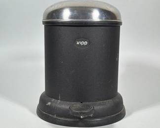 VIPP (DENMARK) MINI PEDAL BIN TRASH CAN | Matte black cylindrical metal pedal bin with an oval 'vipp' badge on the front and a domed stainless-steel lid. The bin sits on a flared round base with an integrated circular foot pedal at the front and a hinge/metal support assembly at the rear. Overall design is compact and utilitarian, emphasizing a simple cylindrical form and domed lid.