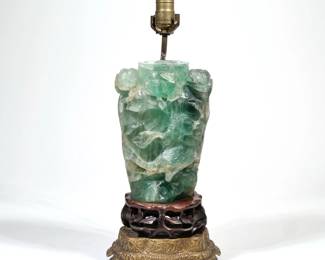 CHINESE CARVED GREEN QUARTZ VASE / LAMP | A carved green quartz vase or jar on a carved wood stand, mounted and electrified on decorative brass footing, the carving depicting a bird amongst flowering branches