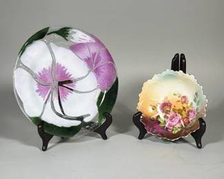 (2pc) ENAMELED FUSED GLASS PLATE AND HAND-PAINTED PORCELAIN SCALLOPED DISH | Kiln-formed enameled glass plate decorated with a large white and purple floral motif and green leaf accents; glass plate diameter 8.75 in. The glass plate shows raised clear glass lines, small air bubbles and fine craquelure in the surface enamel. Scalloped porcelain dish with a blended yellow-green to purple ground and a hand-painted pink rose spray. Underside of the porcelain dish bears a small green backstamp and a recessed foot ring.