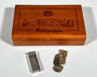 VINTAGE CARVED JADE DRAGON PENDANT AND SWISS-MADE LIGHTER IN MONTEGRAPPA BOX | Wooden hinged Montegrappa box engraved "1912" and "Montegrappa" on the lid contains a carved stone dragon pendant and a silver-tone rectangular lighter. The pendant is carved from a mottled brown-green stone with a pierced hole and a stylized dragon carving. The lighter is slim with a guilloché pattern and a side knurled ignition wheel; the base is stamped "PATENTED" and "MADE IN SWITZERLAND."  Dimensions: h. 2.25 x w. 8.5 x l. 5.25 in (box)