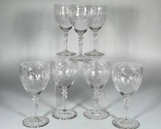 (7pc) CUT GLASS WINE GOBLETS WITH FLORAL CUT BOWLS AND TWISTED STEMS | Set of six clear cut glass wine goblets with all-over floral and foliate cut decoration to the bowl, twisted/spiral-cut stems and round pads on the bases featuring circular impressed dots. h. 6.5 in.; diam. 3 in. Each goblet has a multi-faceted knop at the stem and a slightly tapering bowl with deep wheel-cut leaf and fan motifs. 