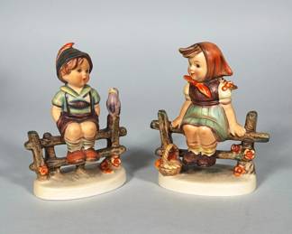 (2pc) W. GOEBEL HUMMEL PORCELAIN FIGURINES | Pair of polychrome glazed porcelain Hummel figurines depicting a boy and a girl seated on a rustic fence, the boy with a small bird and the girl with a basket. Bases are stamped "by W. Goebel" and "West Germany" and show a blue Goebel maker's mark. Each figure is hand-painted in characteristic Hummel colors and sits on an oval molded base. Model numbers and additional impressed marks are visible on the bases.