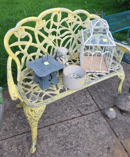 vintage yellow cast iron garden bench featuring an intricate floral scrollwork pattern. 