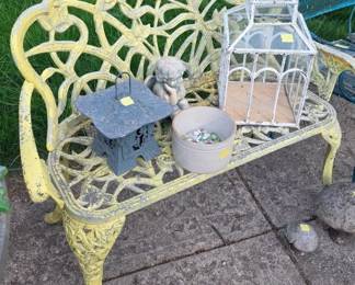 vintage yellow cast iron garden bench featuring an intricate floral scrollwork pattern. 