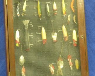 Lot 15. Wall-mounted fishing bait display case full of vintage baits, including Bass-Oreno with glass eyes, Devil's Horse, Bomber, Millsite, feathered spinners, and more. 24" x 18" x 2"