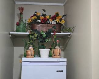 Upright freezer and floral arrangements behind the garage.