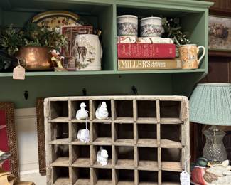 vintage books, mugs, duck figurine, candlesticks, green wooden shelf with hangers