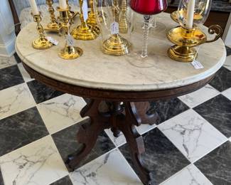 Marble top center table with a collection of brass candlesticks