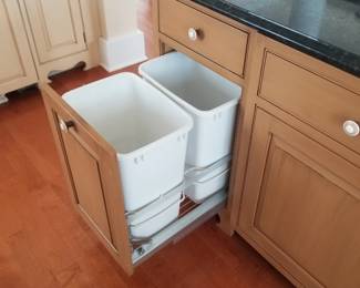 Kitchen cabinetry features a trash corral