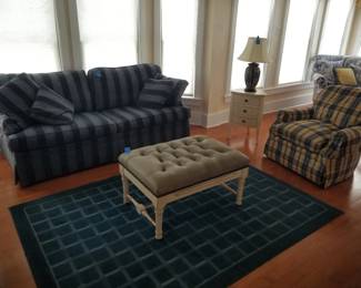 Blue on blue striped sleeper sofa; leather upholstered ottoman; navy area rug
