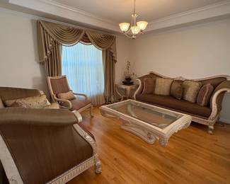 R10 - $1500. Benneti Italia Elegant Living Room Set. Oversized. Has ornate carved wood frames. Includes a comfy sofa, two armchairs, a coffee table with a glass top, and glass top side table. Upholstery is in brown and gold tones. Comes with decorative pillows.  DIMENSIONS:   Sofa approx. 8ft L x 3ft D x 4ft H. Large side chair 60”W x 38”D x 48”H.  Accent chair 31”W x 29”D x 45”H.  Side table 38”W x 38”D x 28”H.  Coffee table 63”L x 41”W x 19.5”H 