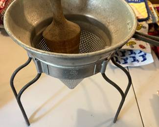 Vintage Wear-Ever aluminum cone sieve with wooden pestle and stand.