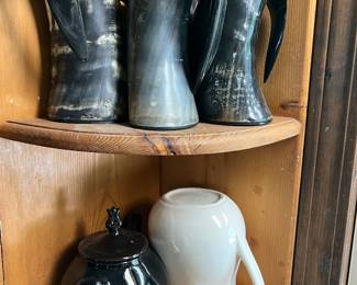 A collection of three natural horn drinking vessels and two ceramic pitchers.