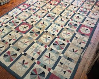 A hooked rug with a repeating pinwheel motif.