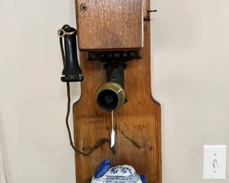 Antique wall telephone featuring a wooden case, dual bell ringer, hand crank, and separate receiver. Iconic early communication piece with strong appeal for collectors and display.
