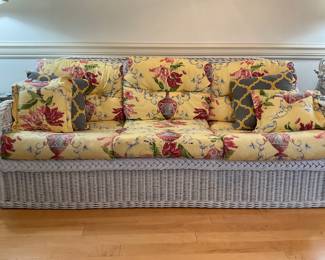 White rattan wicker sofa with removable yellow printed upholstered cushions. Measures 76”x32”x34”