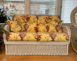 White rattan wicker love seat with removable yellow printed upholstered cushions.. measures 53”x32”x34”