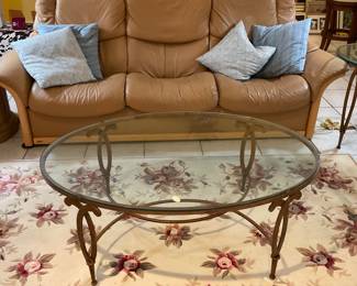 Large tan soft leather sofa with all sections reclining... Oval wrought iron glass top coffee table 