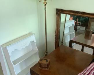 Antique mirror with beveled glass, bathroom white shelf, two floor lamps, and a side table