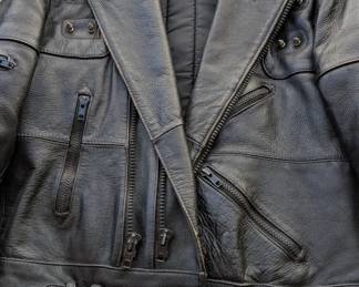 This is a classic Wilsons Leather motorcycle jacket, featuring a belted waist and studded detailing on the lapels and pockets. Based on the "Wilsons" script on the tag and the overall construction, this is likely a vintage piece from the late 1980s or 1990s.
