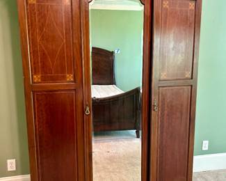 3-door wood armoire with center mirror. Interior has hanging space and shelves.