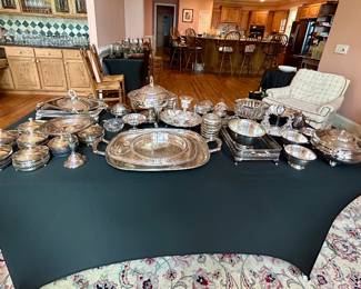 Large collection of silverplate serving pieces including trays, bowls, and covered dishes.